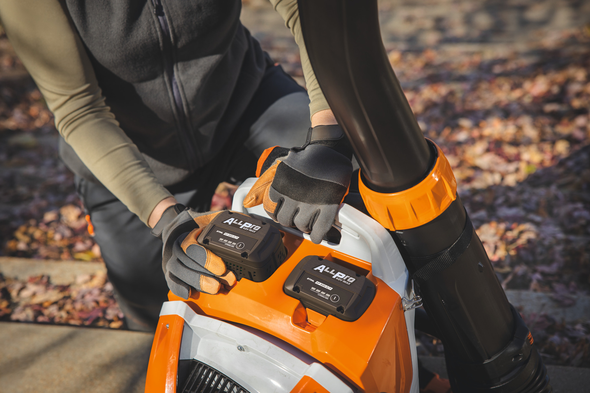 Ein professioneller Landschaftsgärtner setzt den zweiten STIHL-Akku AP 300.0 P in das STIHL-Akku-Rucksackgebläse ein
