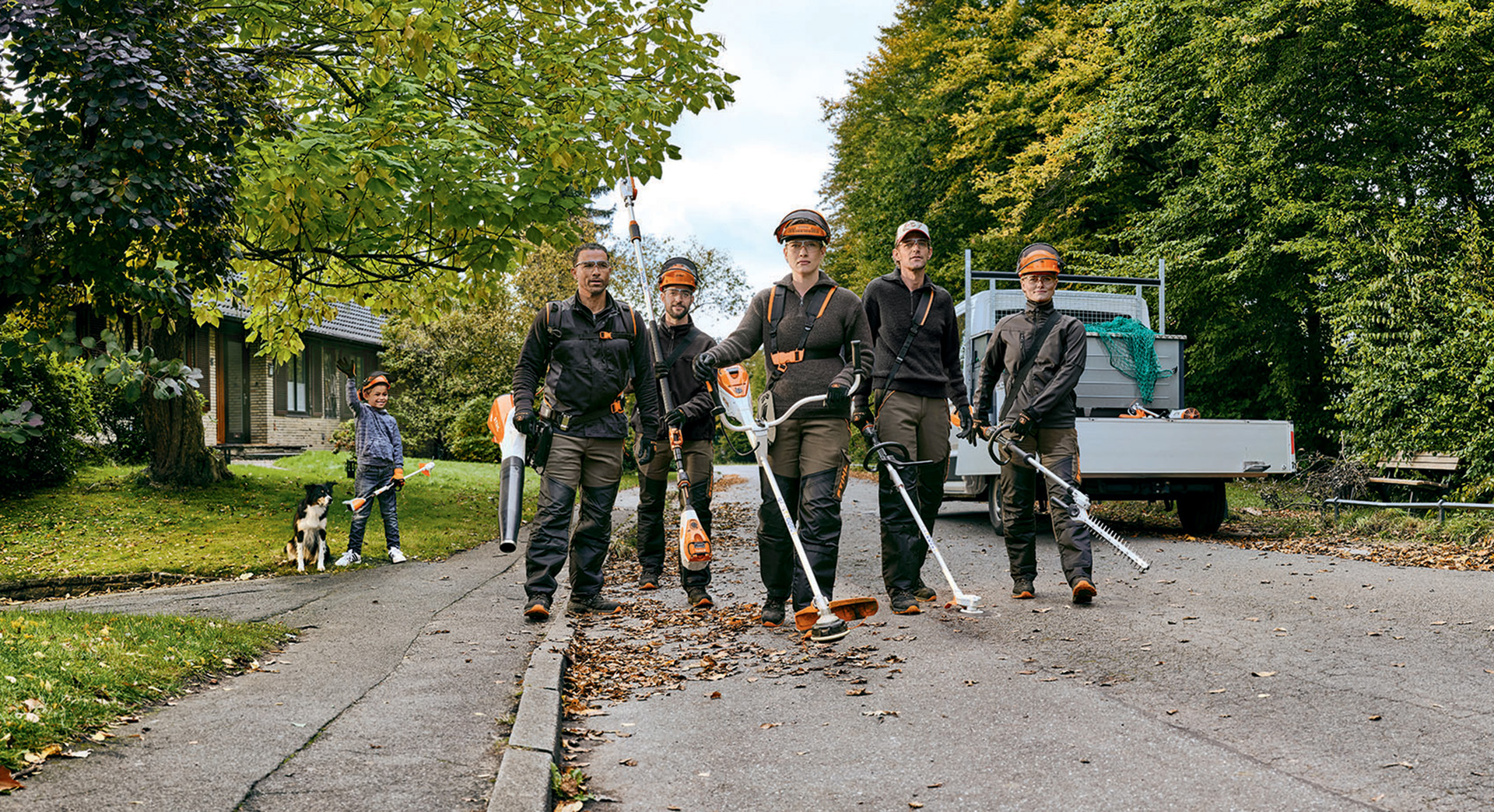 Ein Garten- und Landschaftsbauer Team mit STIHL Profi-Akku-Geräten geht eine Straße entlang.