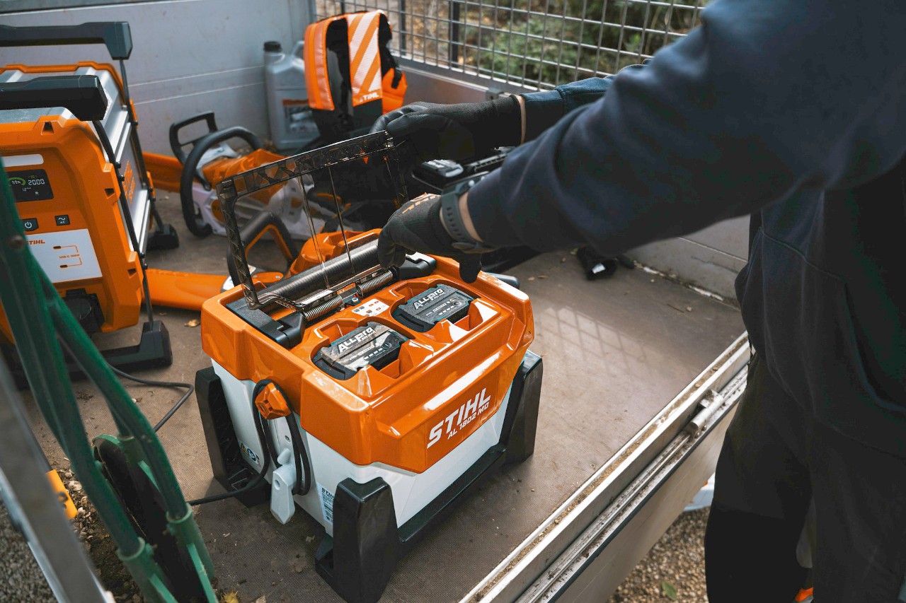  The landscape gardener places the batteries in the charger to recharge them.