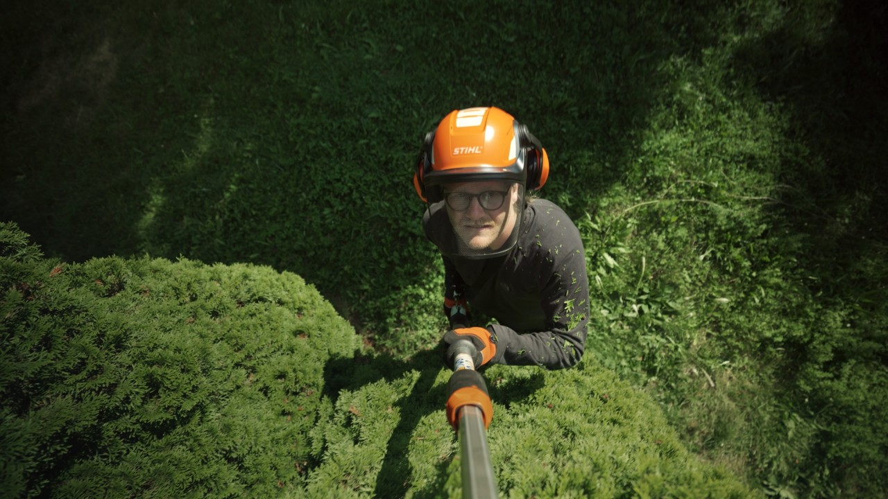 Achille schneidet mit Hochentaster Äste in einem Baum, Gartenarbeit im Grünen, Real People. STIHL People. Kampagne