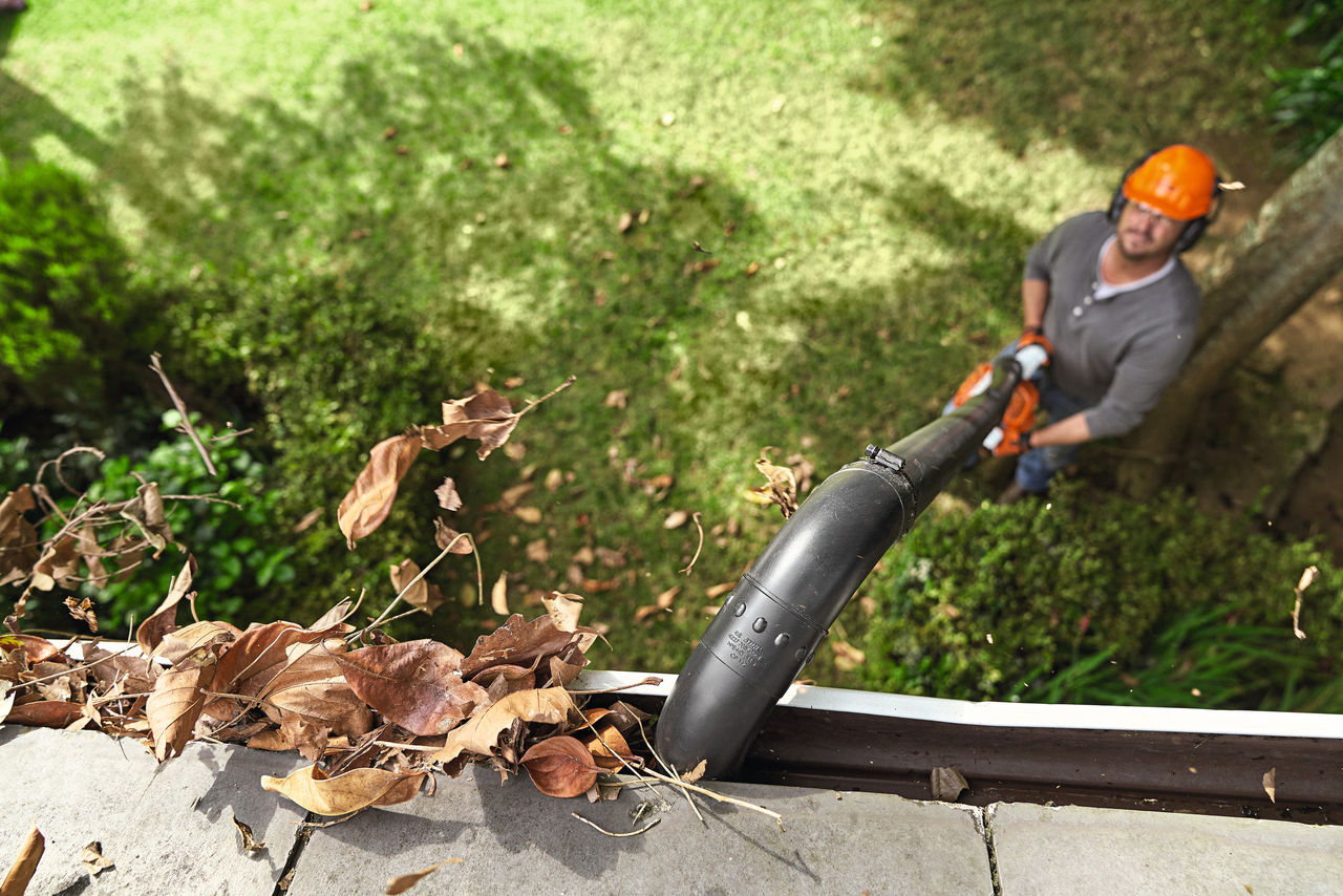 Mann reinigt eine Dachrinne mit dem STIHL Dachrinnenreinigungsset