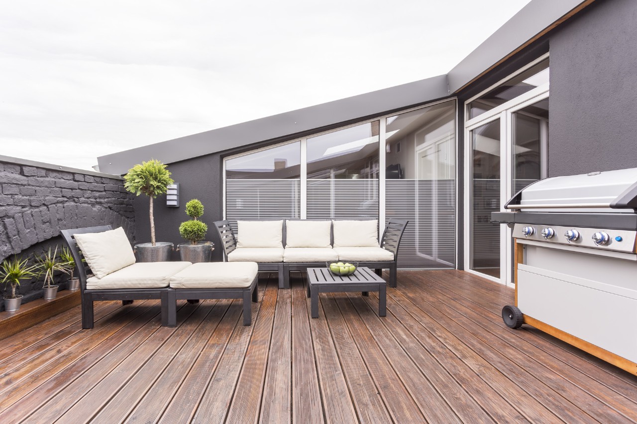 Meubles de jardin, barbecue et plantes sur un toit-terrasse avec plancher en bois