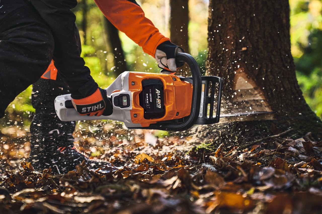 Un professionnel du bois abat des arbres en forêt à l'aide d'une tronçonneuse sans fil de type STIHL MSA260 et d'une batterie ALLPRO