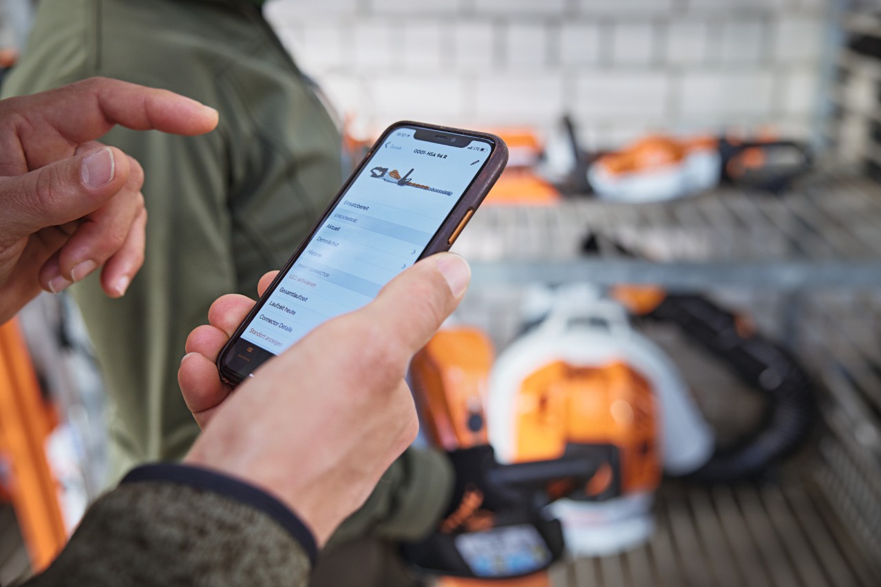 Une personne dans l'entrepôt vérifie la date dans l'application STIHL connected sur son smartphone.
