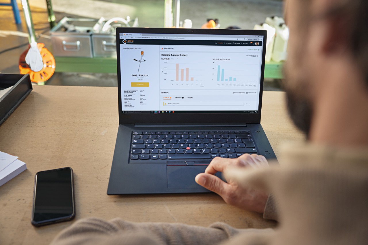 La persona siede davanti al suo computer e controlla lo stato dell'apparecchio con il portale STIHL connected.
