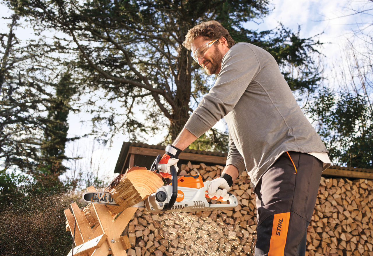 Un uomo che usa lo STIHL MSA 70 per tagliare la legna in giardino
