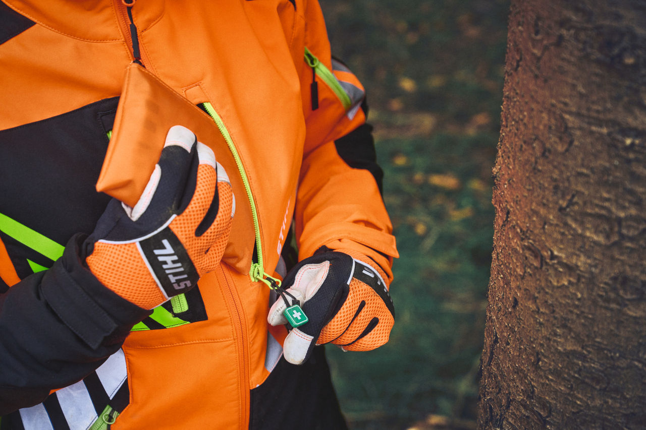 Primo piano di una persona in STIHL ADVANCE FlexTEC con ciondolo a cerniera di primo soccorso ShellTEC nel bosco