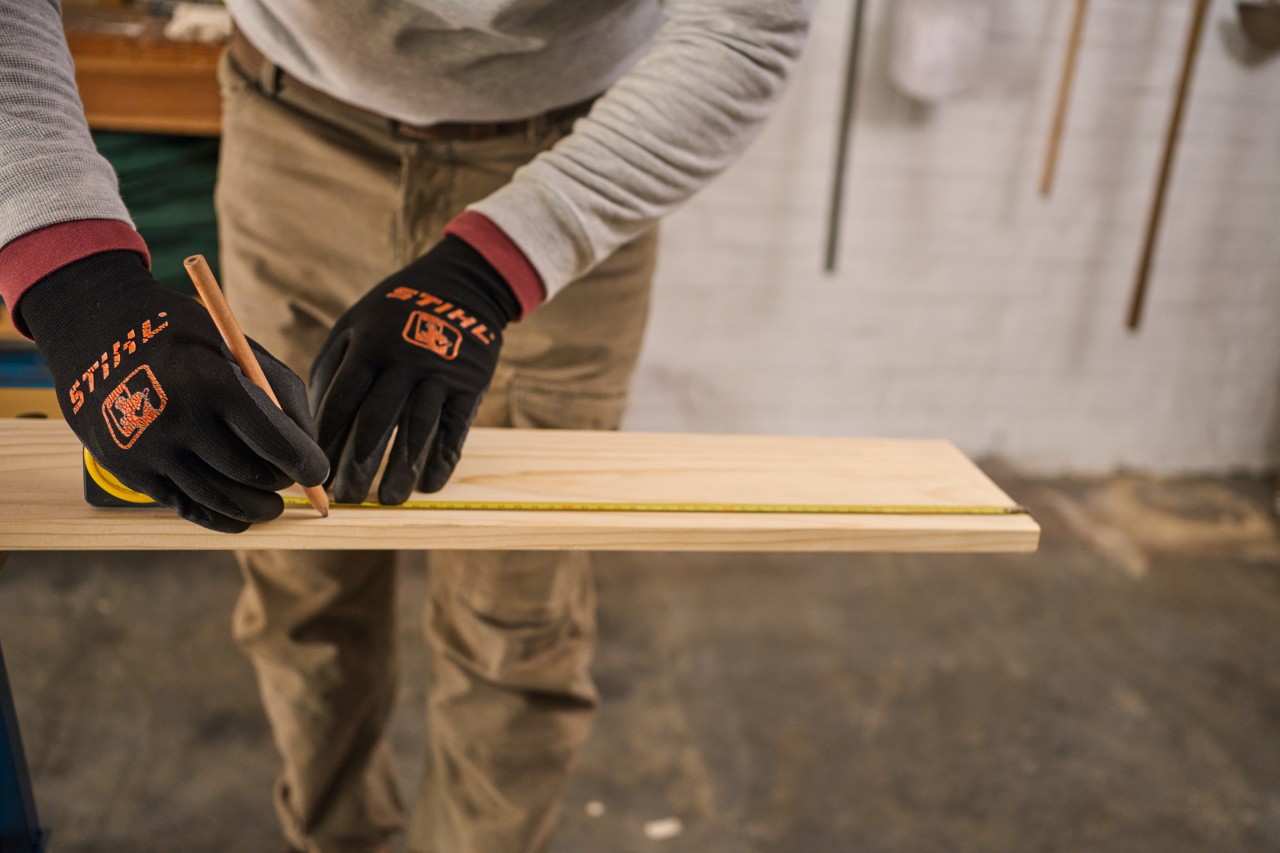 Un uomo segna le misure su un pezzo di legno