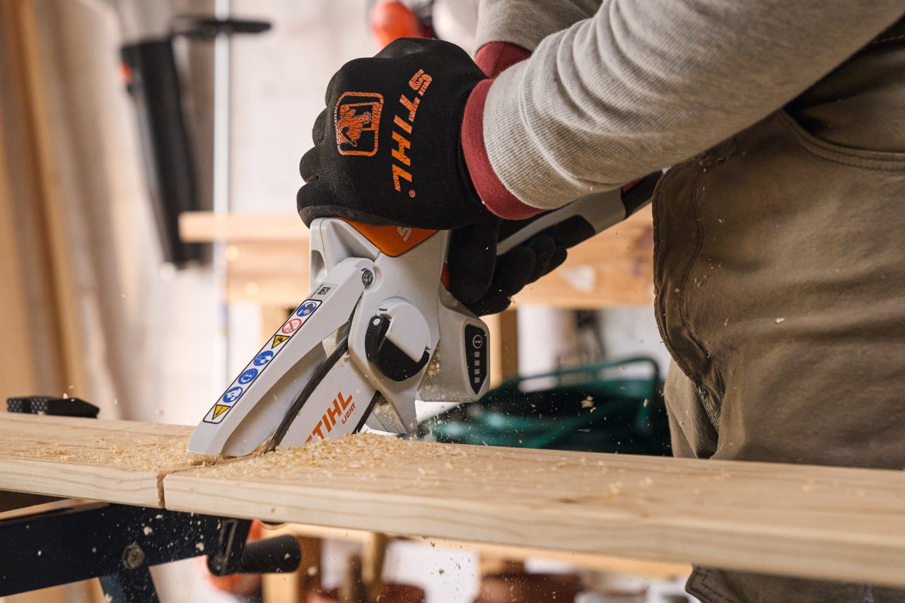 Un uomo taglia le tavole di legno con un potatore a batteria STIHL GTA 26